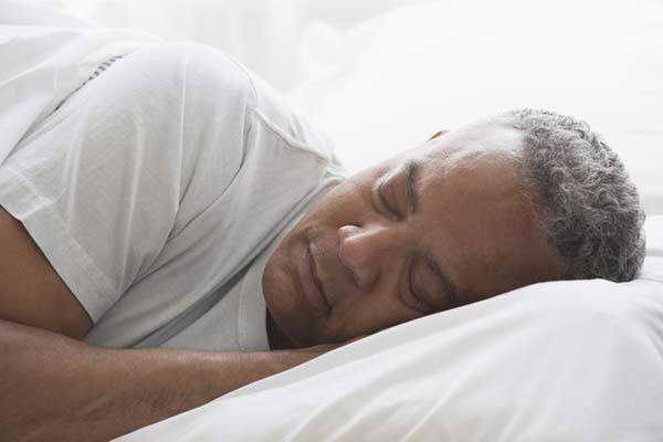 photo of a mature man sleeping in bed on his side