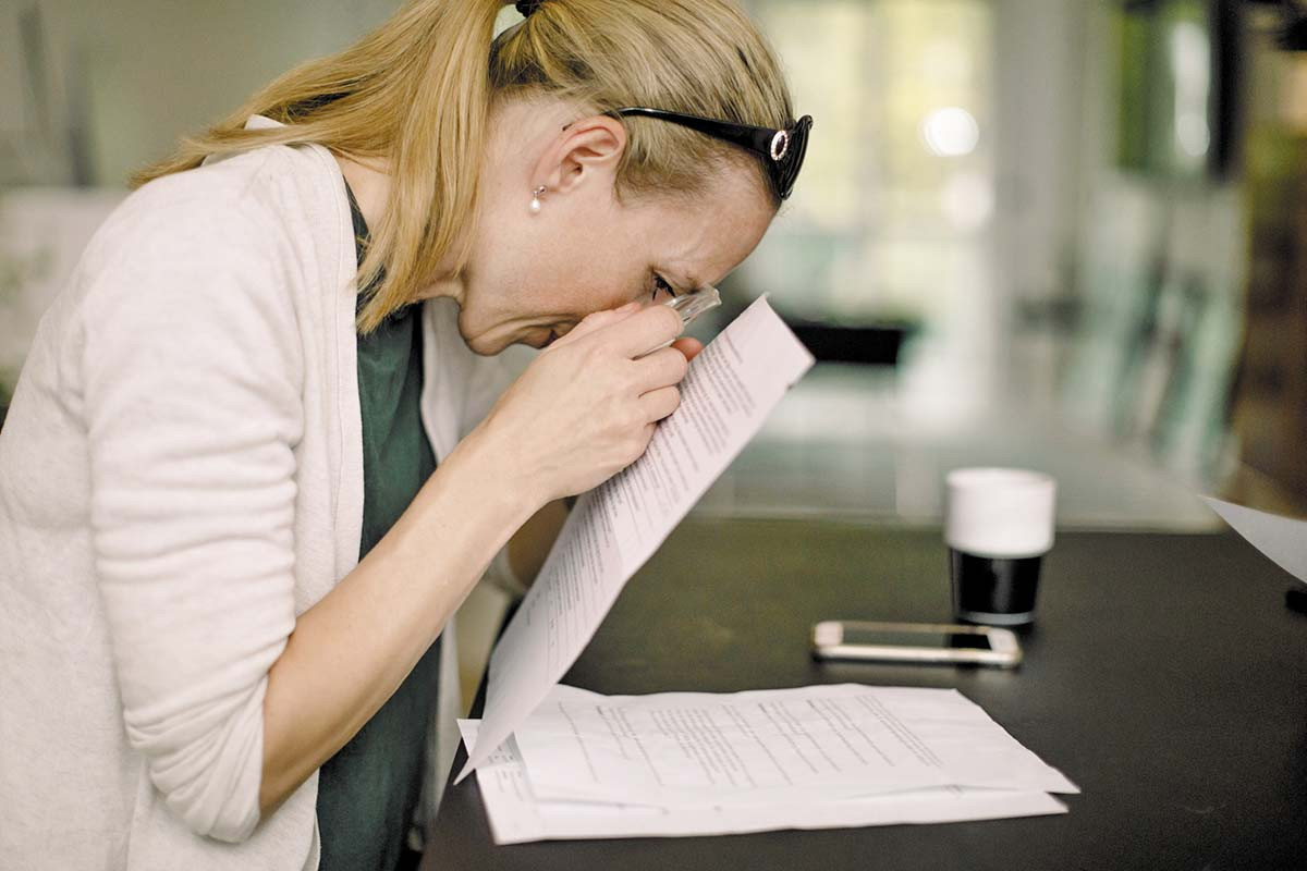 photo of a woman using a magnifier to read text on a piece of paper