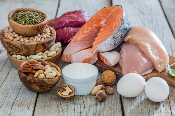 photo of an assortment of high-protein foods including beef, salmon, chicken, eggs, yogurt, and nuts